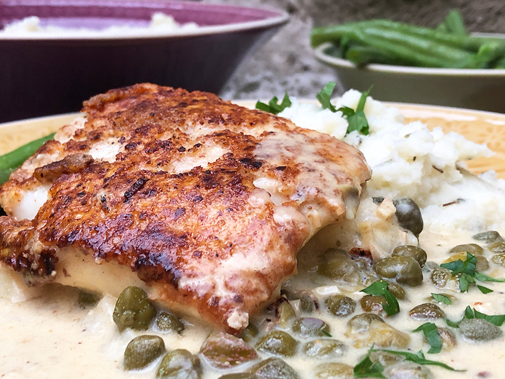 Torsk i piccatasaus på en seng av blomkålmos